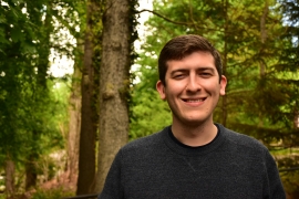 Man in forest smiles and looks forward.